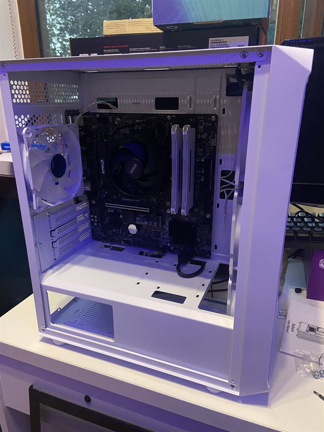 White PC case with motherboard, AMD cooler and memory installed during assembly